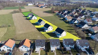 Luftaufnahme eines Neubaugebietes mit bereits errichteten Häusern und freien Baugrundstücken.