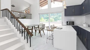 Moderne offene Küche mit Essbereich, Kücheninsel und Bergblick durch große Fenster.