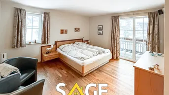 Gemütliches Schlafzimmer mit Holzboden, Zugang zum Balkon und zwei Fenstern.