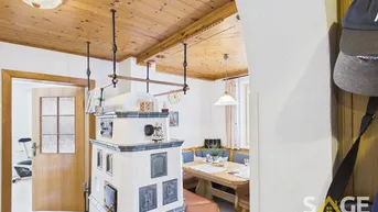 Gemütlicher Wohn-Essbereich mit traditionellem Kachelofen und Holzdecke.