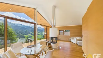 Heller Wohn- und Essbereich mit Panoramablick auf die Berge, Holzböden und einem modernen Kamin.