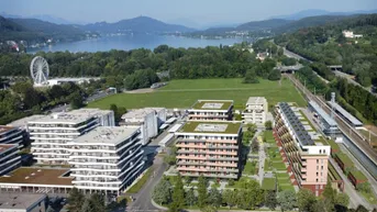 Luftaufnahme eines modernen Wohnkomplexes mit Gründächern, See- und Bergblick, umgeben von viel Grün.
