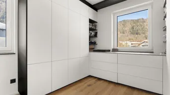 Modernes Schlafzimmer mit Einbauschränken und Bergblick durch das Fenster.