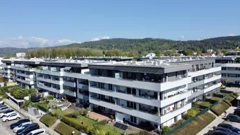 Luftaufnahme eines modernen Wohnkomplexes mit mehreren Gebäuden, Balkonen und Grünflächen.