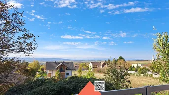 Panoramablick über die umliegende Landschaft mit Häusern und Bergen am Horizont unter blauem Himmel.