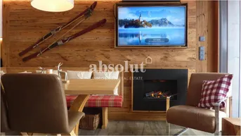 Essbereich mit Holztisch, Sitzbank und integriertem Kamin, umgeben von Holzwänden im alpinen Stil.