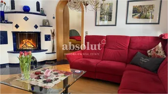 Helles Wohnzimmer mit rotem Sofa, blau gefliestem Kamin und Holzboden.