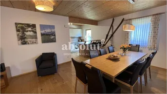 Geräumiger Wohn-Essbereich mit Holzboden, Holzbalkendecke und rustikalen Dekorationen.