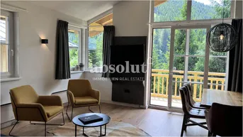 Helles Wohn- und Esszimmer mit großen Fenstern, Holzboden und Bergblick.