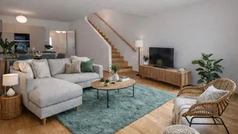 Gemütliches Wohnzimmer mit Ecksofa, Teppich und Holztreppe, die in die obere Etage führt.