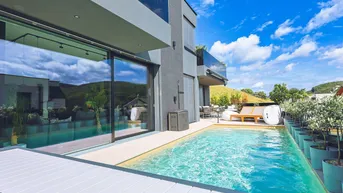 Moderner Außenbereich mit langem Pool, großen Glasfronten und komfortablen Liegeflächen.