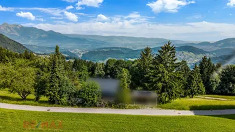 Weitläufiger Panoramablick über grüne Täler und majestätische Berge unter blauem Himmel.
