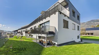 Modernes Mehrfamilienhaus mit Balkonen und gepflegter Rasenfläche in sonniger Lage.