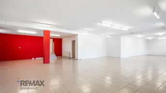 Geräumiger, heller Geschäftsraum mit Fliesenboden und einer auffälligen roten Säule, bereit zur Gestaltung.