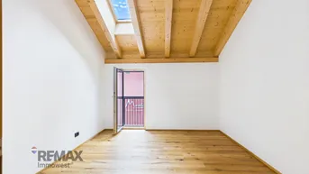 Helles Schlafzimmer mit Holzbalkendecke, Dachfenster und französischem Balkon.