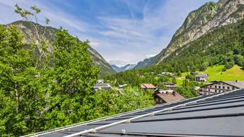 Panoramablick über das Tal und die umliegenden Berge von einem Dachbereich aus.