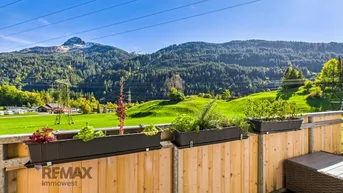 Balkon mit Holzboden und Blumenkästen bietet einen weiten Blick auf die umliegende Berglandschaft.