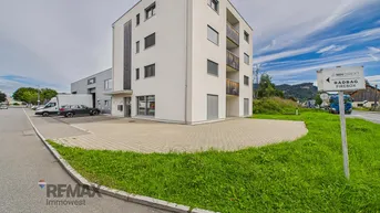 Modernes Mehrfamilienhaus mit weißer Fassade und Balkonen in ländlicher Umgebung.