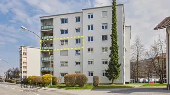 Mehrfamilienhaus mit mehreren Etagen und Balkonen in einer städtischen Umgebung.