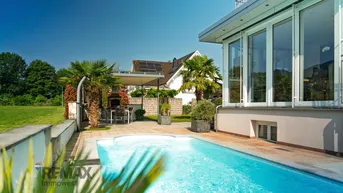Außenbereich mit Pool, Terrasse und Essbereich, umgeben von Palmen und Grünflächen.