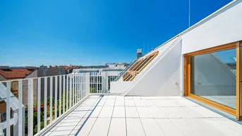 Geräumige Dachterrasse mit weißem Metallgeländer und Blick über die Stadt.
