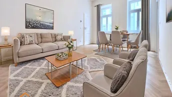 Helles Wohn- und Esszimmer mit modernem Mobiliar, Parkettboden und großen Fenstern.