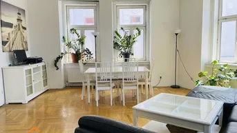 Helles Wohn- und Esszimmer mit Fischgrätparkett, weißem Mobiliar und großen Fenstern.
