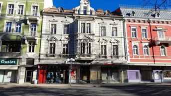 Historische Gebäudezeile mit Geschäften im Erdgeschoss und Wohnungen darüber in der Stadt.