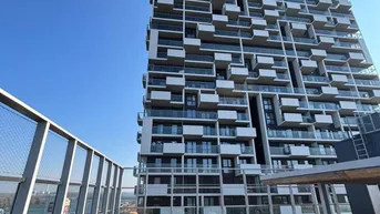 Moderner Wolkenkratzer mit vielen Balkonen und einer Dachterrasse, die einen weiten Blick bietet.