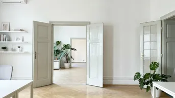 Helles Büro mit Fischgrätparkett, weißen Wänden und Blick in angrenzende Räume.
