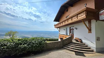 Gebäude mit traditioneller Holzfassade und weitem Blick über die Landschaft und Berge.