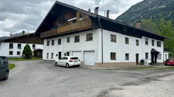 Großes Wohnhaus im alpinen Stil mit Holzbalkonen und Garagen in ländlicher Umgebung.