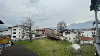 Weitläufiger Blick über die Nachbarschaft mit Grünflächen und Bergen im Hintergrund.