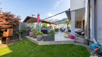 Große Terrasse mit Gartenmöbeln, Rasenfläche und Bergblick im Hintergrund.