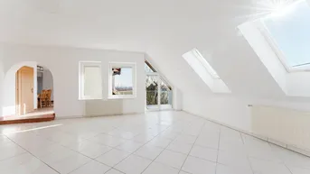 Helles, geräumiges Wohnzimmer im Dachgeschoss mit Fliesenboden, Dachfenstern und Zugang zum Balkon.