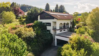 Ansicht des Hauses mit Balkonen, umgeben von üppiger Vegetation und Bäumen.