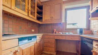 Rustikale Küche mit Holzschränken, Terrakotta-Fliesen und integriertem Geschirrspüler.