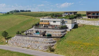 Luftaufnahme des modernen Hauses mit terrassiertem Garten, Pool und weitem Blick über die Landschaft.