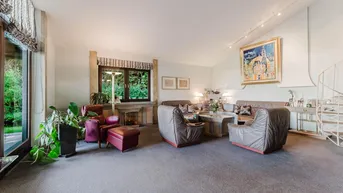 Großzügiges Wohnzimmer mit Teppichboden, Kamin und Blick in den Garten.