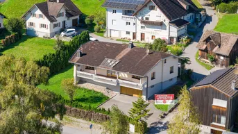 Luftaufnahme des Hauses und der umliegenden Wohngegend mit Verkaufsanzeige.
