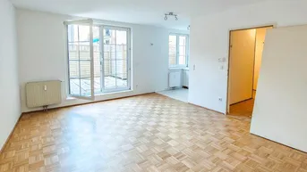 Helles Wohnzimmer mit Parkettboden und Zugang zu einer Außenterrasse.