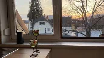 Blick aus der Küche bei Sonnenuntergang mit ländlicher Umgebung und einem Haus im Hintergrund.
