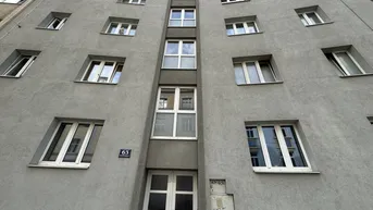 Die Fassade eines mehrstöckigen Wohngebäudes mit zahlreichen Fenstern und einem zentralen Eingangsbereich.