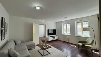 Helles Wohnzimmer mit modernem Sofa, Teppich und Blick auf die Umgebung.