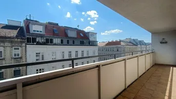 Geräumiger Balkon mit Fliesenboden und Blick auf die umliegenden Stadtgebäude unter blauem Himmel.