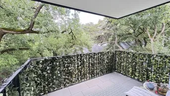 Geräumiger Balkon mit grüner Bepflanzung am Geländer und Blick ins Grüne.