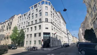 Modernes Eckgebäude in städtischer Umgebung mit vielen Fenstern und Rollläden, gut gepflegt.