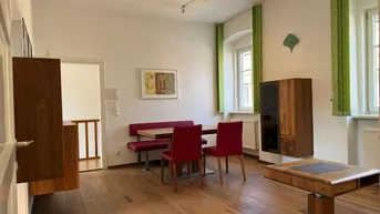 Geräumiger Wohn- und Essbereich mit Holzboden, roten Stühlen und Blick nach draußen.