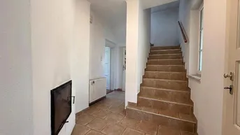 Eingangsbereich mit gefliestem Boden, Treppe und einem eingebauten Kamin.