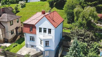 Vogelperspektive eines charmanten Hauses mit rotem Ziegeldach und umgebender grüner Landschaft.